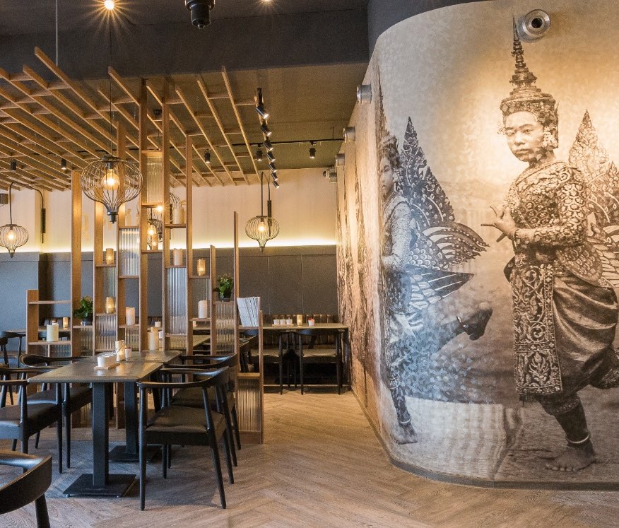 Eetzaal van Station Point Thai Food met houten lamellen als roomdivider en een grote muurschildering van Thaise danseressen